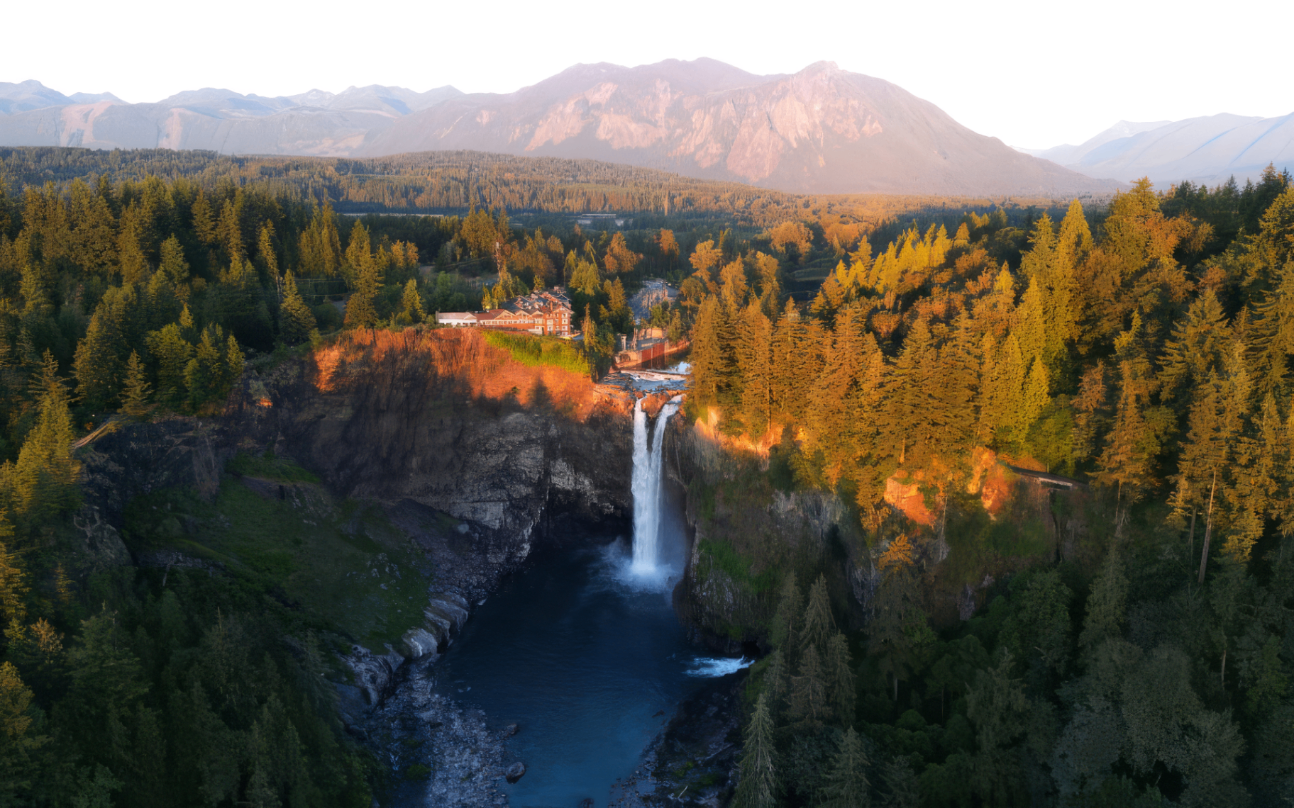 Snoqualmie Falls with Salish Lodge and Cascade mountains at sunrise